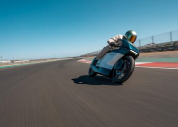 Electric bike racing through a sharp corner on a smooth asphalt track.