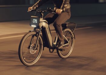 Electric bike with drained battery being pedaled manually on a city street at sunset