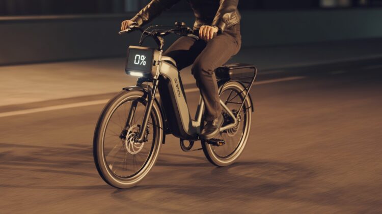 Electric bike with drained battery being pedaled manually on a city street at sunset